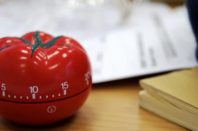 Timer em formato de tomate colocado em cima de uma mesa de madeira