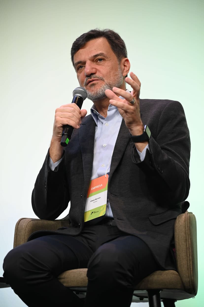 Líbano Barroso, homem branco, com barba grisalha e terno sem gravata, fala no palco da Conferência Na Prática.