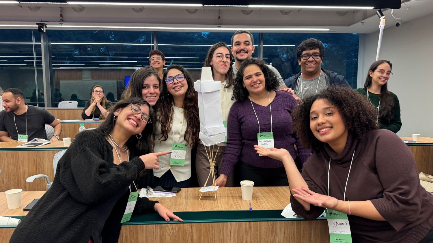 8 jovens posam na frente de foguete construído com plástico durante dinâmica do Carreira de Excelência 2026