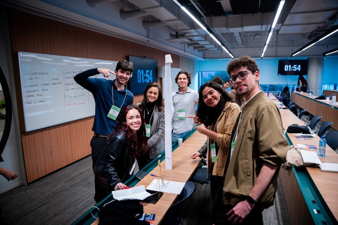 Jovens posam para foto ao lado de uma torre feita com copos plásticos durante dinâmica do Carreira de Excelência de setembro de 2026