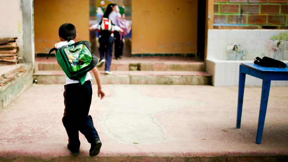 Criança entrando na sala de aula com mochila