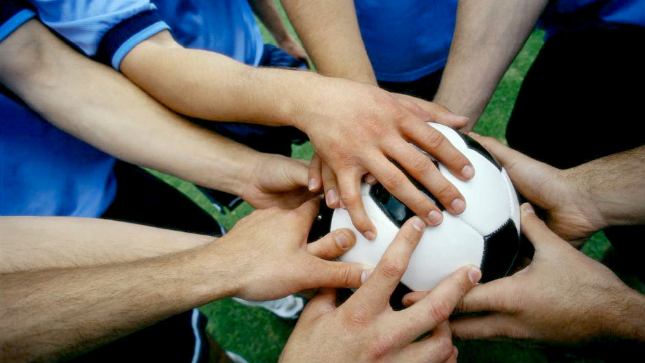 Time de futebol põe as mãos na bola antes do jogo