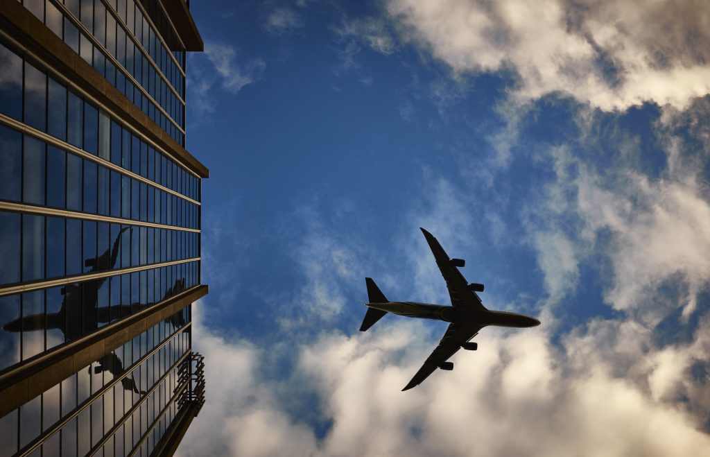 Avião voando acima de prédio