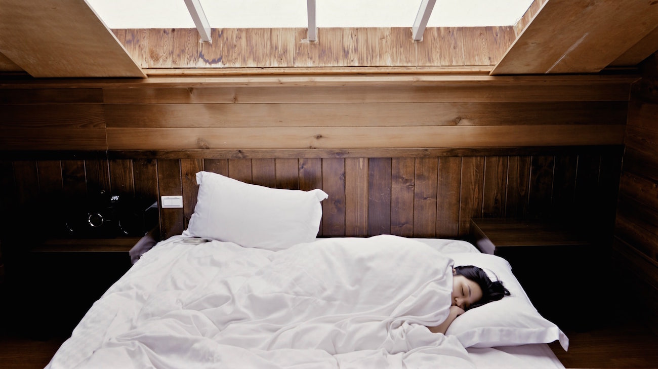 Mulher dormindo em cama confortável sob claraboia