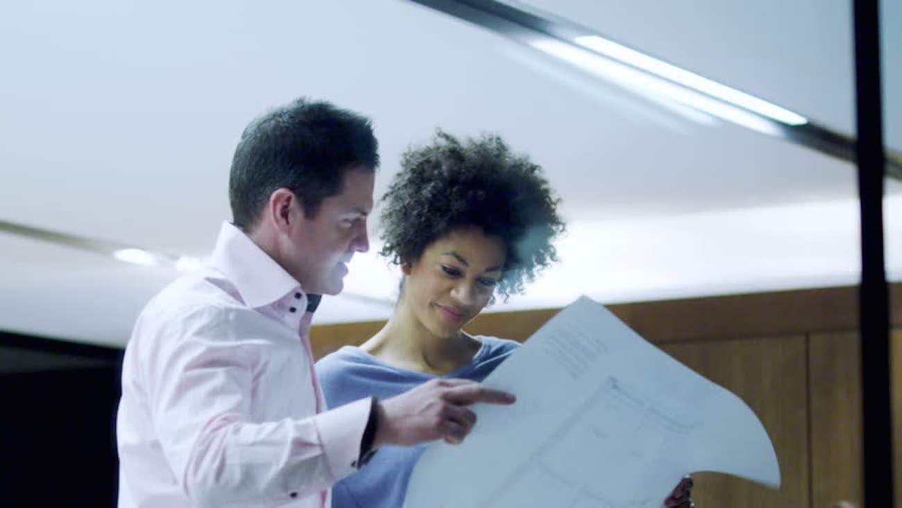 Homem e mulher lendo papel em ambiente de trabalho - Como escolher seu programa de trainee?