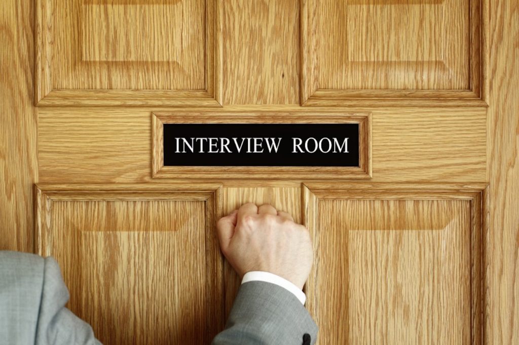 Homem batendo à porta de sala de entrevistas