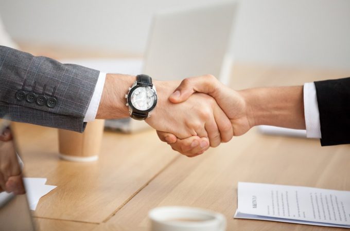 Fusões e Aquisições Close up view of handshake, two businessmen in suits shaking hands as concept of trust, good partnership deal, signing contract agreement at meeting, gratitude for help support in business