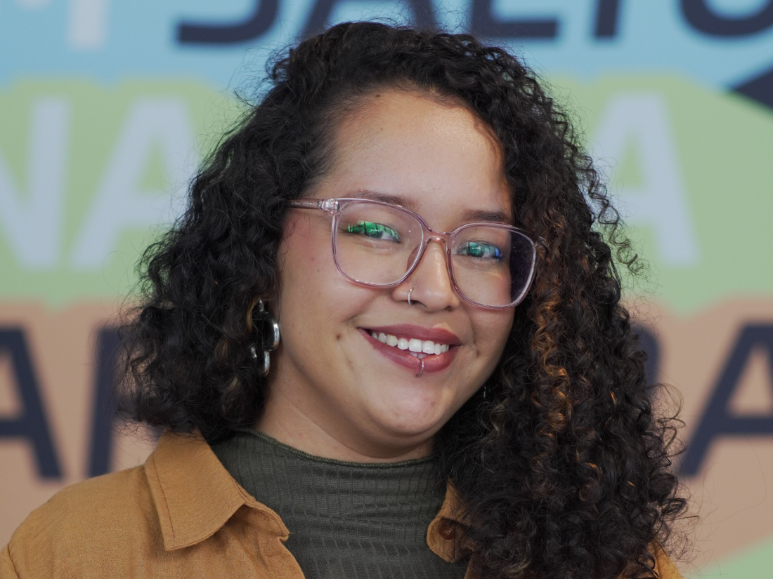 Moça negra de cabelo cacheado sorri para foto durante a Conferência de Carreira 2026